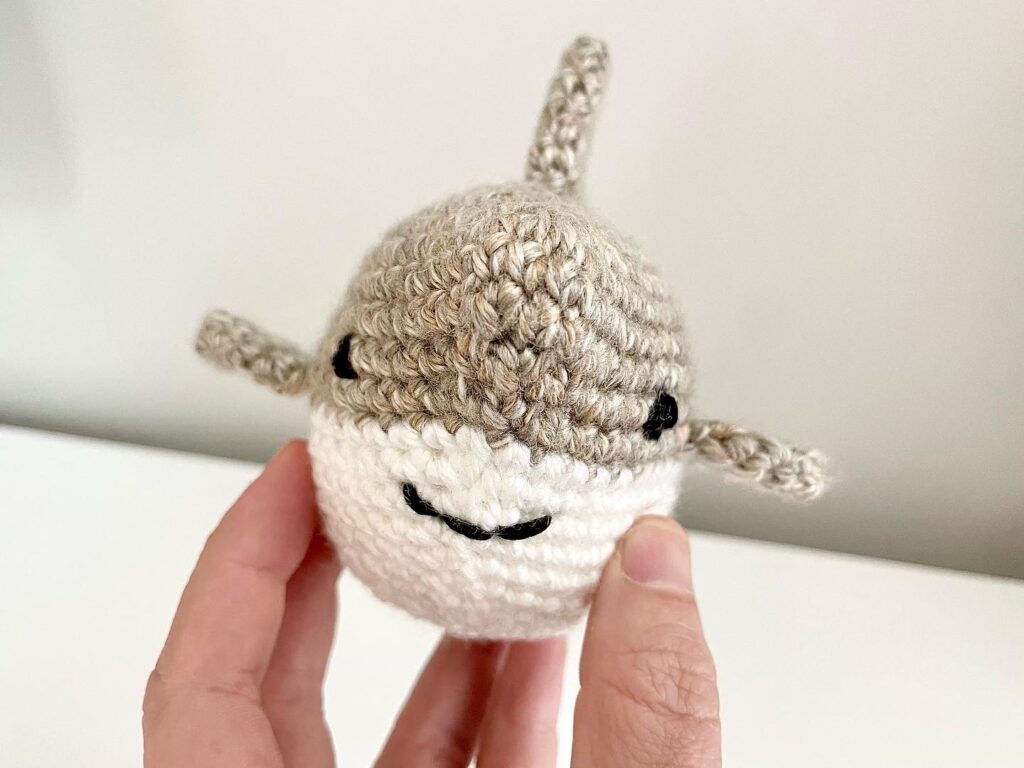 smiling crochet baby shark in tan and white front view